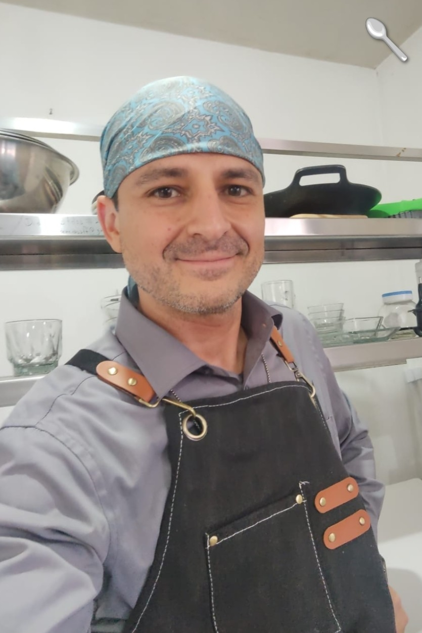 Retrato profesional de elchefhd en cocina equipada, usando mandil negro y paliacate azul.